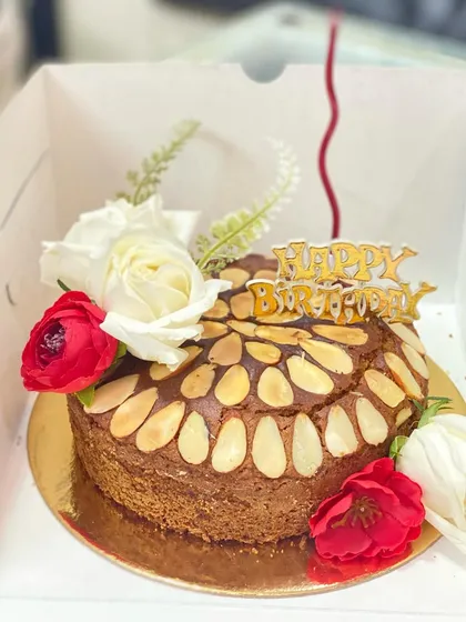 A whole wheat jaggery cake decorated with flowers, a healthier option for a birthday celebration.