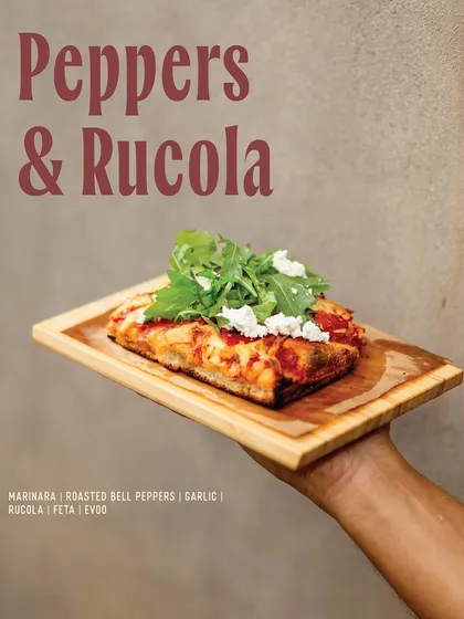 Our Peppers & Rucola slice, a fresh and vibrant option with roasted bell peppers, garlic, feta, and fresh arugula.