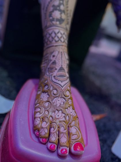 A close-up of a foot covered in a dense floral mehandi design, showcasing the intricacy of the artwork.