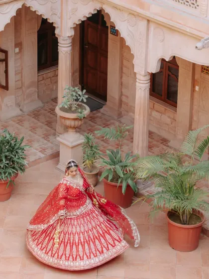 A classic bridal portrait of our bride twirling in her stunning red lehenga within the majestic arches of a Rajasthan palace.