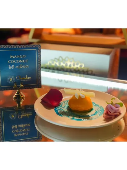 A tropical delight. This Mango Coconut dessert is a refreshing and beautifully plated sweet, reflecting a fusion of flavors with a nod to local tastes, as seen on the Gujarati menu sign.