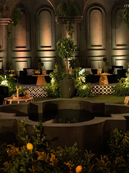 For a unique sangeet, we created a dramatic 'Lemon Garden' at night, using moody lighting, lush greenery, and a central water feature to craft an enchanting experience.