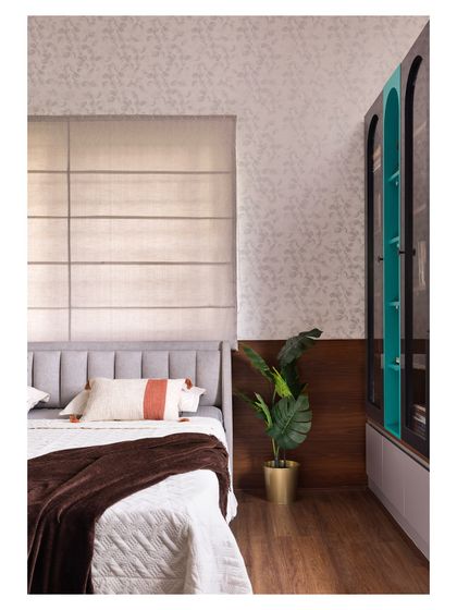 A detail shot highlighting the material palette in this bedroom. The design combines wooden flooring, a textured wallpapered accent wall, and a custom arched bookshelf with a bold teal interior.