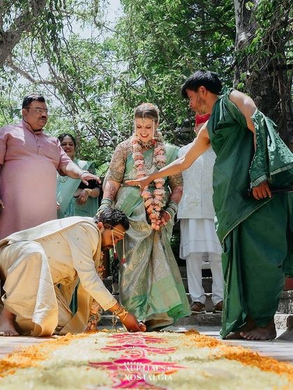 The groom touches the bride's feet as a sign of respect during a traditional ritual, surrounded by family.