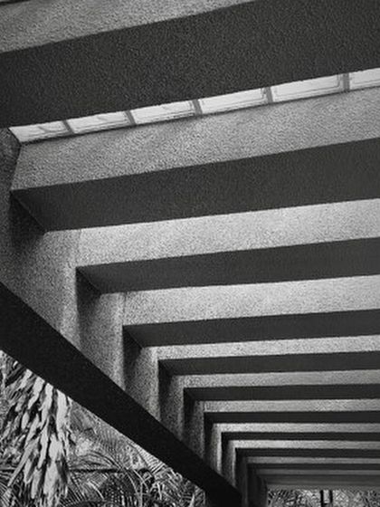 The play of light and shadow brings my designs to life. Here, the strong lines of concrete beams create a powerful rhythm, while a skylight filters soft light from above, demonstrating how texture and light can define an atmosphere.