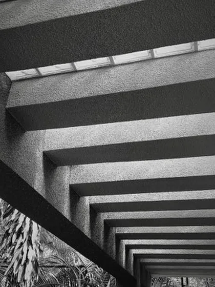 The play of light and shadow brings my designs to life. Here, the strong lines of concrete beams create a powerful rhythm, while a skylight filters soft light from above, demonstrating how texture and light can define an atmosphere.