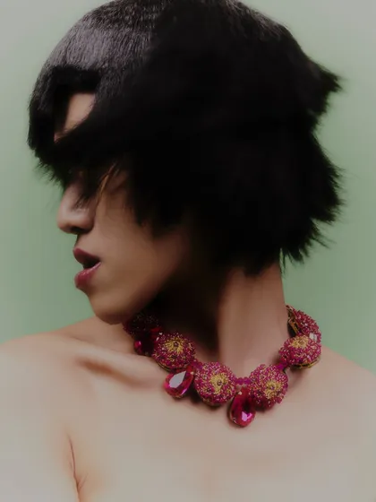 A profile shot showcasing another intricate, ruby-toned necklace. The styling is all about letting the statement jewelry piece be the star.