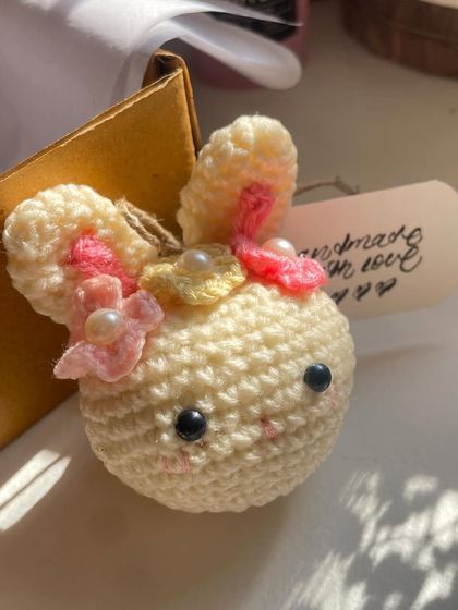 A cute little rabbit keychain to brighten up your day. This sweet amigurumi bunny is adorned with tiny flowers and pearls, making it an extra special accessory.