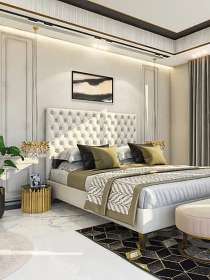 An elegant bedroom design featuring classic wall mouldings and a tufted, button-back headboard. The color palette is a sophisticated mix of cream, gold, and charcoal, creating a serene and luxurious atmosphere.