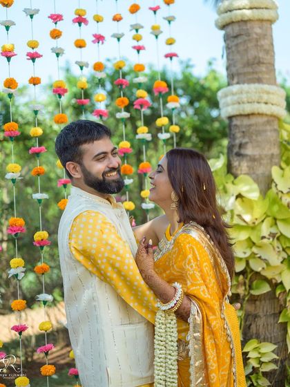 A candid, joyful interaction in front of the floral decor at their Goa Haldi. Their genuine smiles and laughter are what make this photo so special.