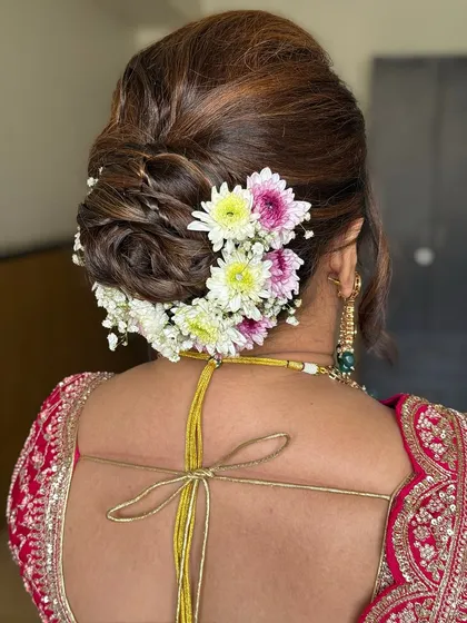 A bridal hairstyle is the crown to the final look. This classic floral bun, woven with fresh flowers, is a timeless choice that adds a touch of tradition and elegance, completing the bride's vision for her wedding day.