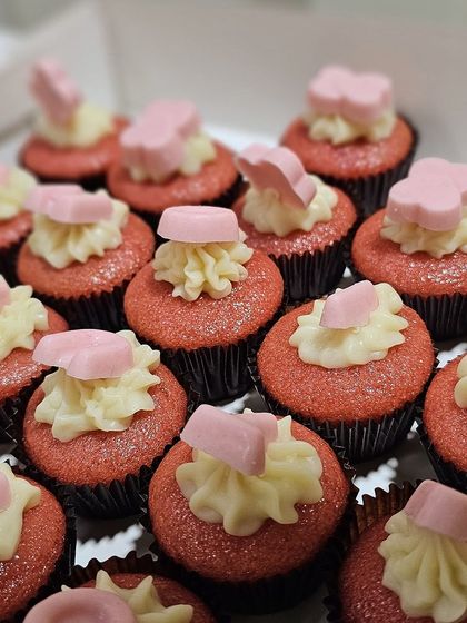 A batch of our mini whole wheat red velvet cupcakes, each topped with cream cheese frosting and a delicate pink chocolate heart.