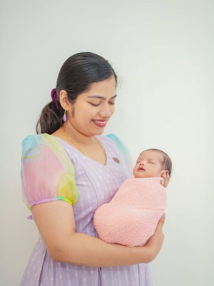 A mother smiling as she cradles her baby. These portraits are designed to feel natural and relaxed, providing a comfortable experience for Bangalore families.