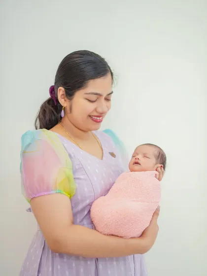 A mother smiling as she cradles her baby. These portraits are designed to feel natural and relaxed, providing a comfortable experience for Bangalore families.
