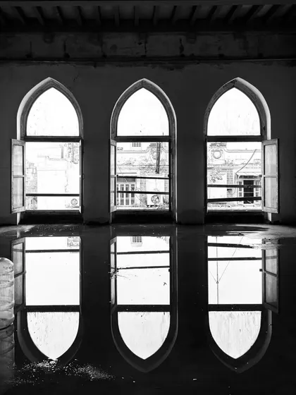 A moment of unexpected beauty on a construction site. The reflections of these three arched windows in the water filled floor create a sense of symmetry and calm amidst the raw, unfinished space.