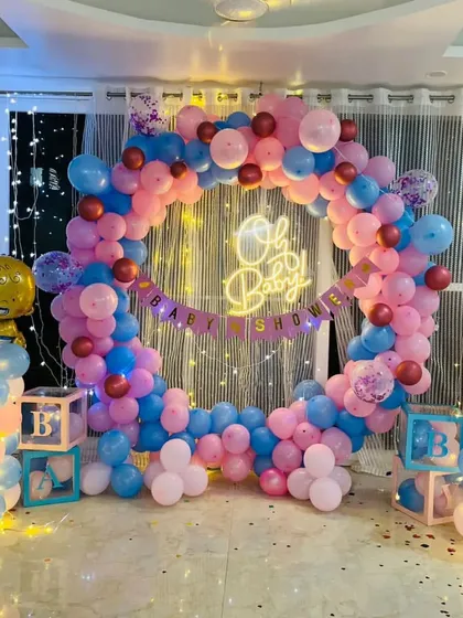 An 'Oh Baby' shower with a circular balloon arch in pink and blue, illuminated with fairy lights.