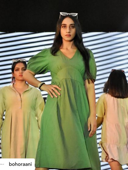 A model confidently walking the runway in our green V-neck midi dress with puff sleeves. This showcases our ability to create simple yet chic everyday western wear.