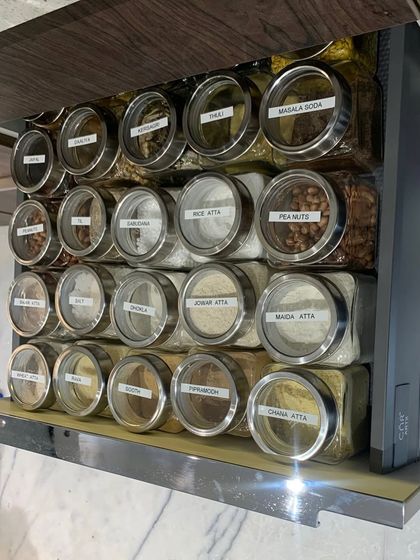A pull-out vertical pantry rack filled with labeled jars of flours and other staples. This is an incredibly space-efficient solution for modern kitchens.