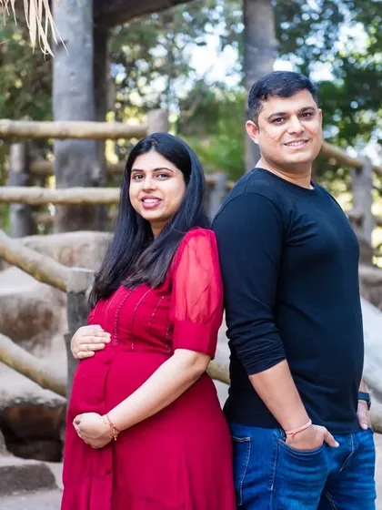 A relaxed portrait of a couple standing back-to-back on a bridge, looking confident and happy as they await their baby.