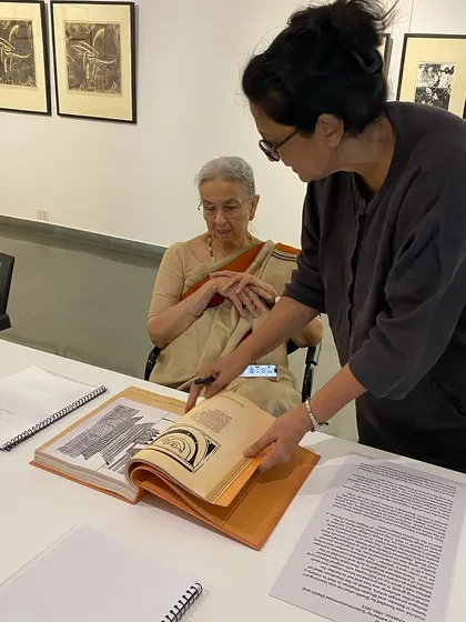 Curator Pushpamala N showing Nilima Sheikh the archival books for the exhibition.