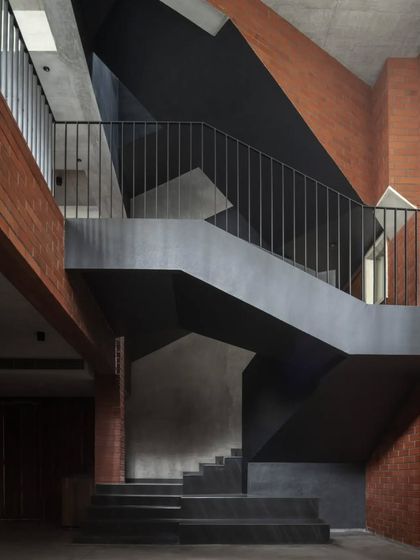The sculptural staircase of the Brick House is a central feature, its dark, geometric form providing a strong counterpoint to the warm brick walls.