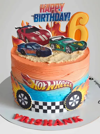 A fiery Hot Wheels cake for a 6th birthday. The orange and blue ombre frosting mimics the Hot Wheels logo, and the cake is topped with edible images of racing cars.