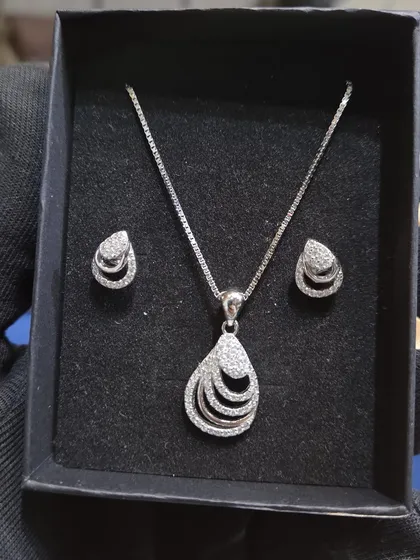 A close-up of a 925 silver chain and pendant set with matching earrings. This layered teardrop design is elegant and modern.