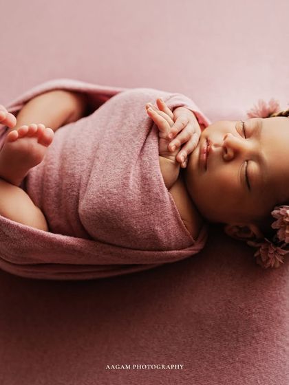 Tiny toes, a button nose, and dreams as pure as morning light. This baby is wrapped in a lovely pink swaddle, with a floral headband adding a touch of nature.