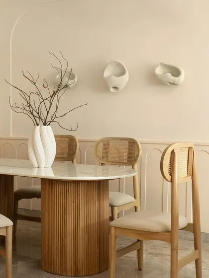 A close-up of the dining table, where a sculptural white vase with dry branches creates a simple, organic centerpiece. The design is minimal, grounded, and deeply calming.