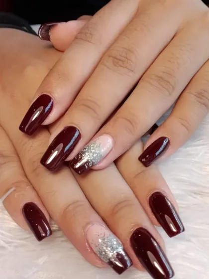 A rich, deep red polish on square-shaped extensions, with a modern accent nail featuring a glittery reverse French tip.