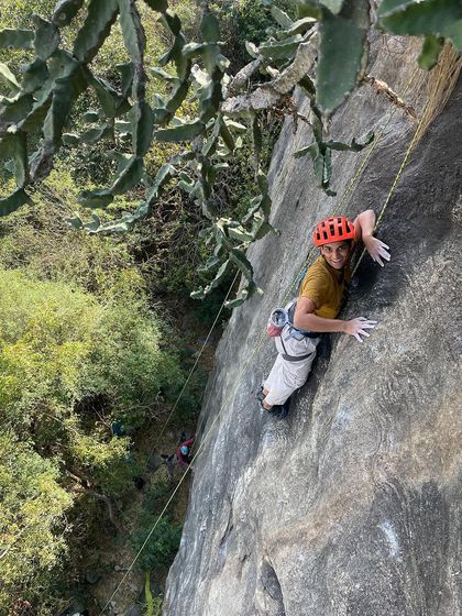 A climber chalks up mid route at Varlakonda, framed by the beautiful texture of the rock and surrounding trees.