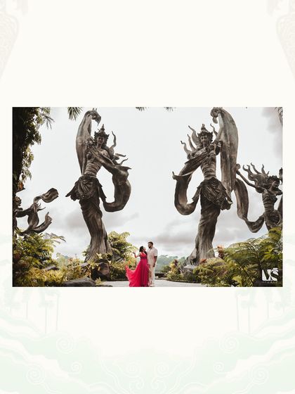 A grand, symmetrical shot of the couple standing between two massive statues in Bali. The composition emphasizes the scale of the location and creates a powerful, legendary feel.