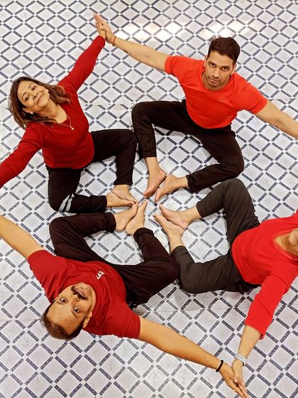 An aerial view of a four-person Acro Yoga mandala. This symmetrical pose, known as 'star', requires communication and equal effort from everyone.