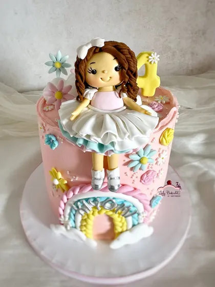 Somewhere over the rainbow! A sweet cake with a custom doll topper, a pastel rainbow, and delicate flowers.