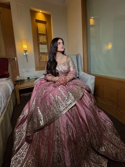 A full-length shot of the Roka outfit. The soft glam makeup perfectly complements the elegant pink and gold lehenga.