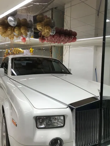 A shot from the Lucky Motors event, where elegant ceiling balloons float above a classic white Rolls Royce, enhancing the showroom's luxurious feel.