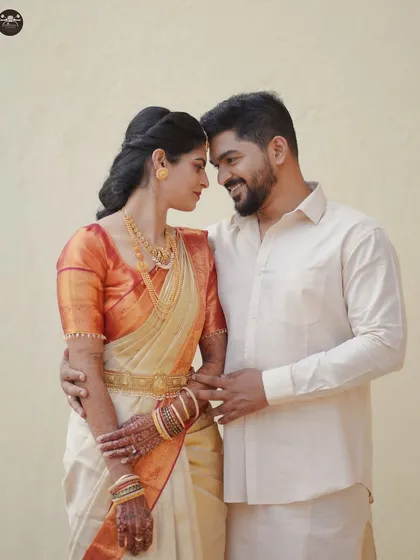 A South Indian couple shares a gentle, candid moment. The bride, in her traditional silk saree and gold jewelry, and the groom look at each other, showcasing the warm, natural style I bring to traditional wedding portraits.