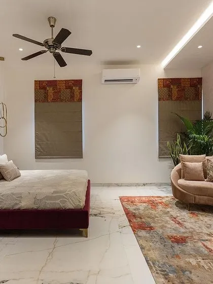 A master bedroom from the Vailankanni Villa project, featuring our custom bed with a deep red channel-tufted headboard and a gracefully curved chaise lounge.