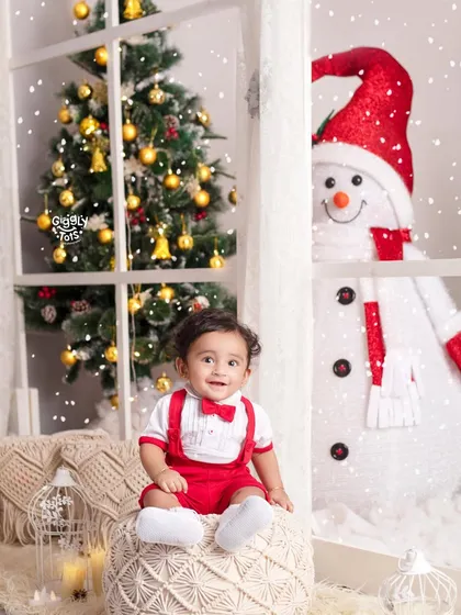 A classic Christmas scene with a happy baby, a friendly snowman, and a twinkling tree.
