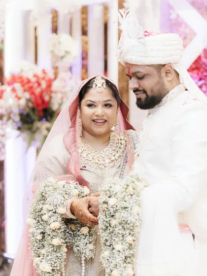 A happy, candid moment during the Varmala ceremony. The bride's joyful expression as she stands with her groom is infectious. These are the memories that will always bring a smile.