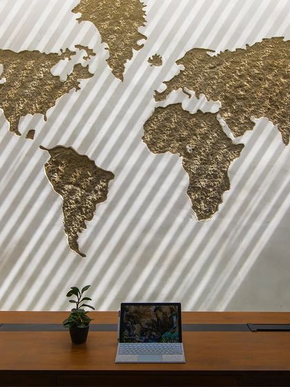 The 'Acutely Bare' office features a custom world map with a textured, foiled finish. The play of light from the window creates diagonal stripes, adding another layer to the design.