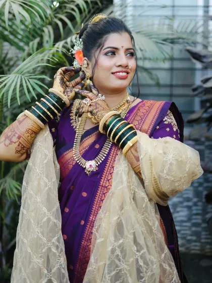 Adjusting her earring, this shot highlights the detailed henna and traditional green bangles, essential parts of a Marathi bride's look.