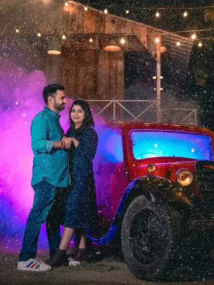 I use cinematic effects like artificial rain and colored smoke to add drama and emotion to your pre-wedding photos. Here, a couple shares a romantic moment by our vintage red car, creating a scene straight out of a movie.