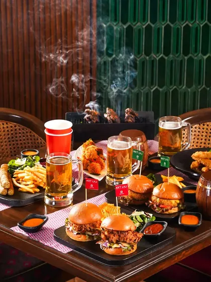 A full table spread for an Oktoberfest celebration, complete with burgers, wings, fries, and mugs of beer. This shot conveys a sense of a hearty, communal feast.