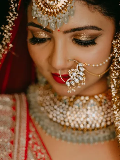 A detailed close-up of the bold golden eye makeup and classic red lip, a perfect combination for a North Indian bride.
