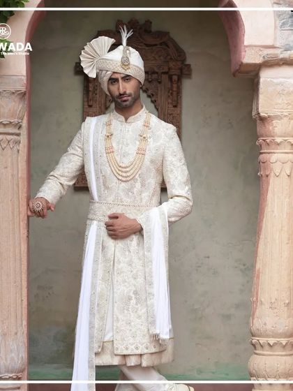 Another view of the groom against heritage pillars, his white sherwani standing out in its timeless beauty. The Shauhar collection is where artistry embraces heritage.