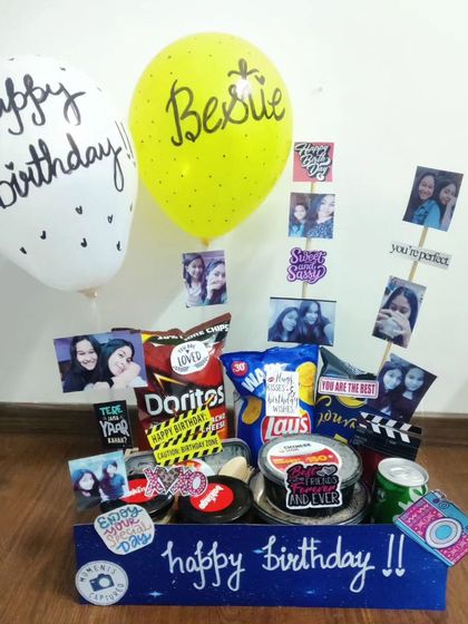 A birthday hamper created especially for a bestie. It features a collection of their favorite snacks like Doritos and Lays, surrounded by memorable photos and topped with a 'Bestie' balloon.