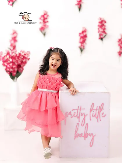 A 'Pretty Little Baby' indeed. This three year old birthday girl shines in her beautiful pink dress against a clean, modern studio backdrop with floral accents.