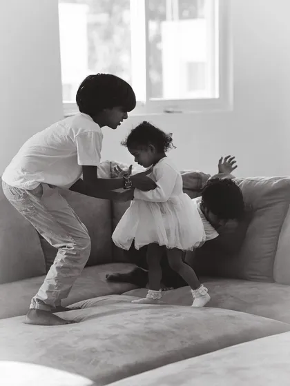Family life is beautifully chaotic. This candid shot captures the playful energy of siblings interacting at home, showcasing the honest, unposed style of my black and white family photography.