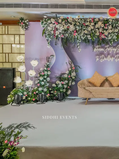 A side angle of the lavender-themed engagement stage, highlighting the asymmetrical floral design and the soft glow of the custom neon hashtag.